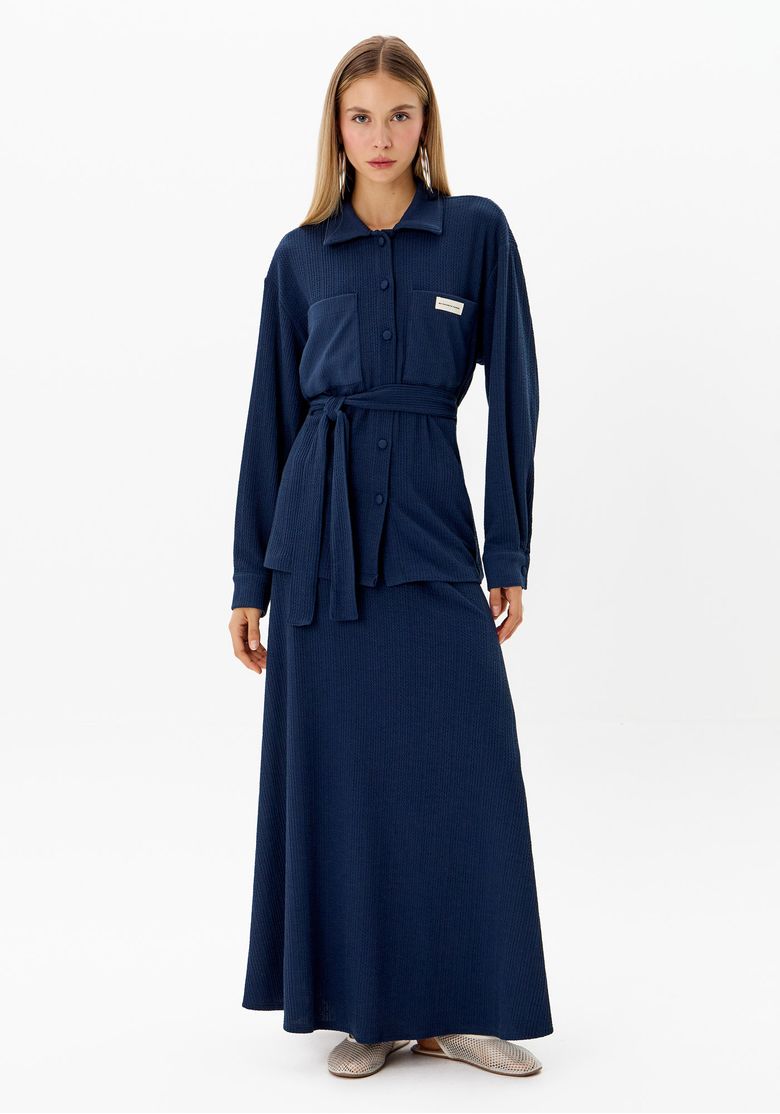 Modelo usando a camisa azul combinada com saia longa, vista completa.