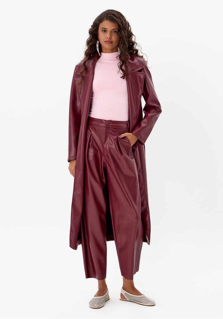 Modelo vestindo calça baggy vermelha com casaco longo combinando e top rosa.