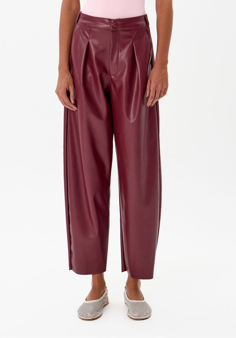 Detalhe da calça baggy vermelha mostrando pregas frontais e cintura marcada.