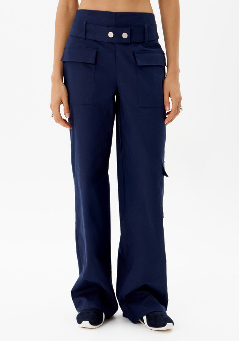 Detalhe frontal da calça reta azul com bolsos utilitários.