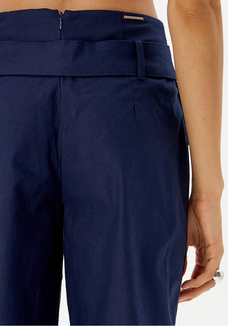 Detalhe do cós e fechamento da calça reta azul.