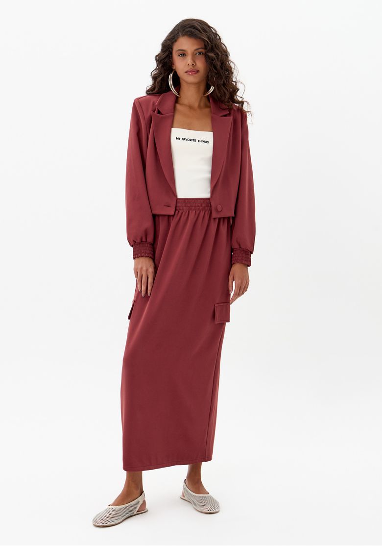 Modelo usando saia super midi vermelha de alfaiataria com cós de elástico e bolso lateral, em look urbano feminino