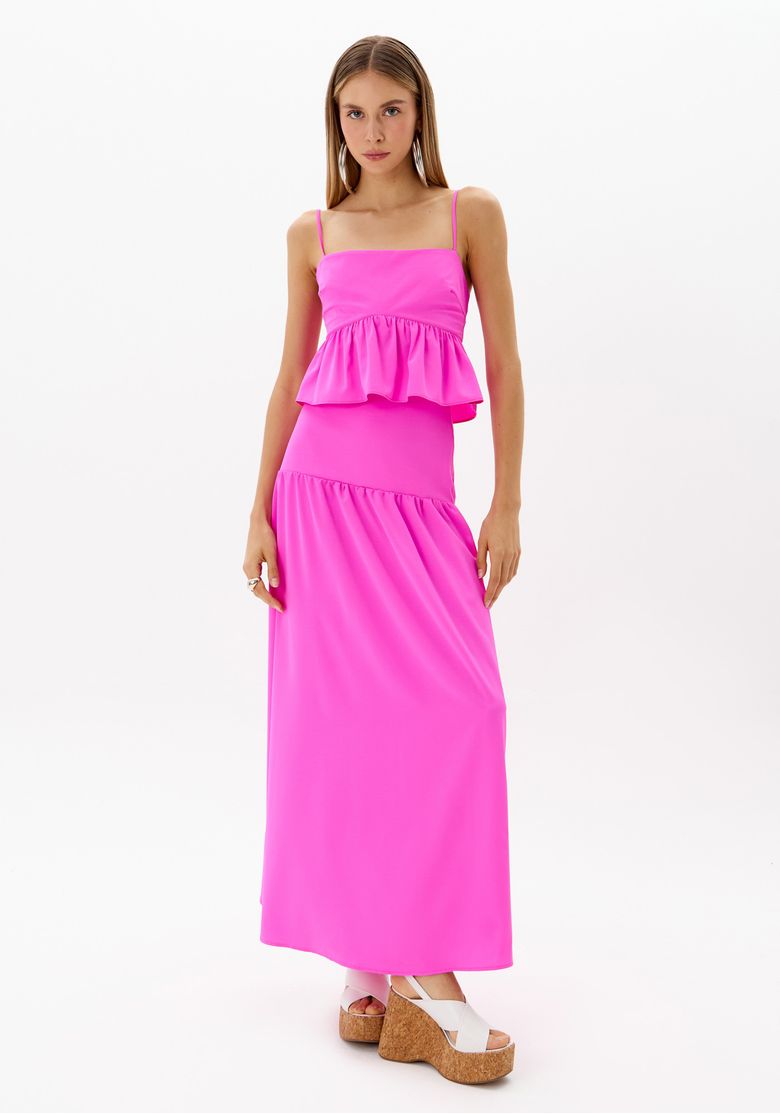 Modelo frontal usando saia super midi rosa com top cropped de alças finas, saia cintura média em tecido plano leve 100% poliéster, look para jantar e ocasiões casuais elegantes