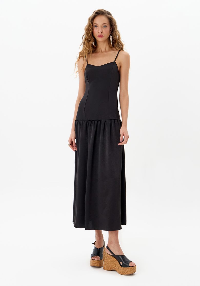 Vestido super midi preto de alças finas vista frontal em modelo sobre fundo branco, comprimento super midi e saia franzida