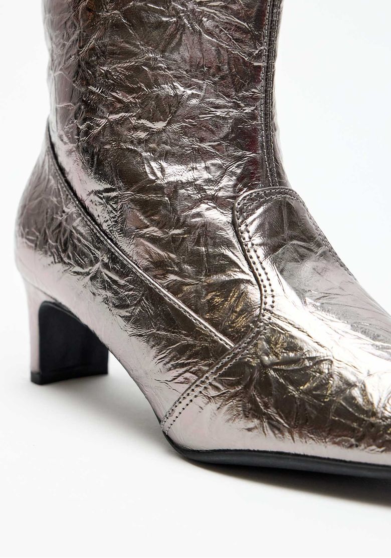 Par de botas cano curto femininas pretas com acabamento metalizado e bico fino, fotografadas lado a lado para mostrar silhueta e proporções.