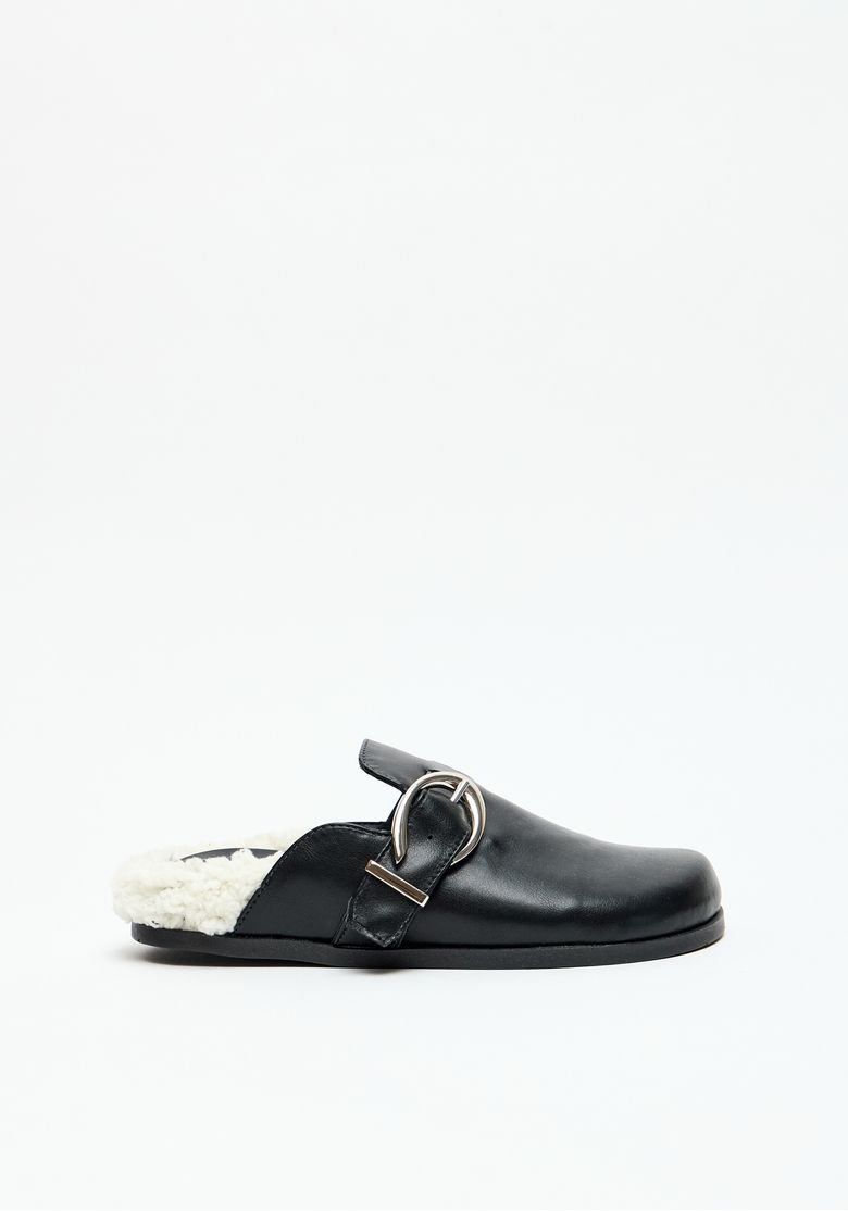 Mule feminino preto com fivela metálica e forro em pelo sintético, vista lateral.