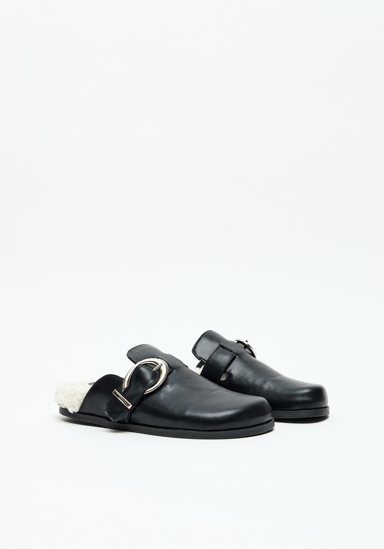 Mule feminino preto com fivela metálica e forro em pelo sintético, vista diagonal.