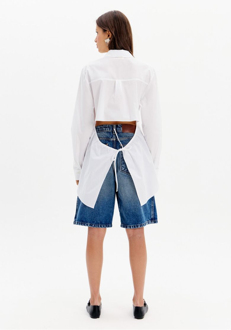 Vista traseira da bermuda jeans feminina comprimento bermuda com camisa branca recortada e sapato preto