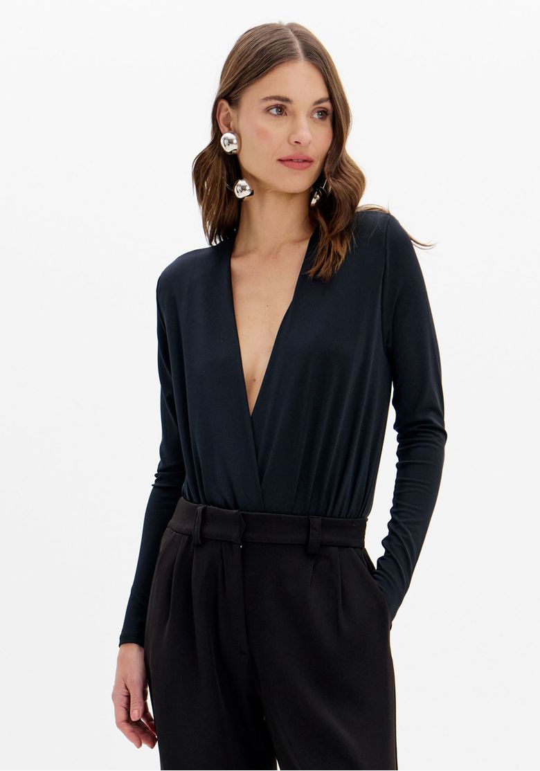 Modelo usando body preto manga longa transpassado com decote em V profundo combinado com calça de alfaiataria preta, vista frontal em look elegante feminino
