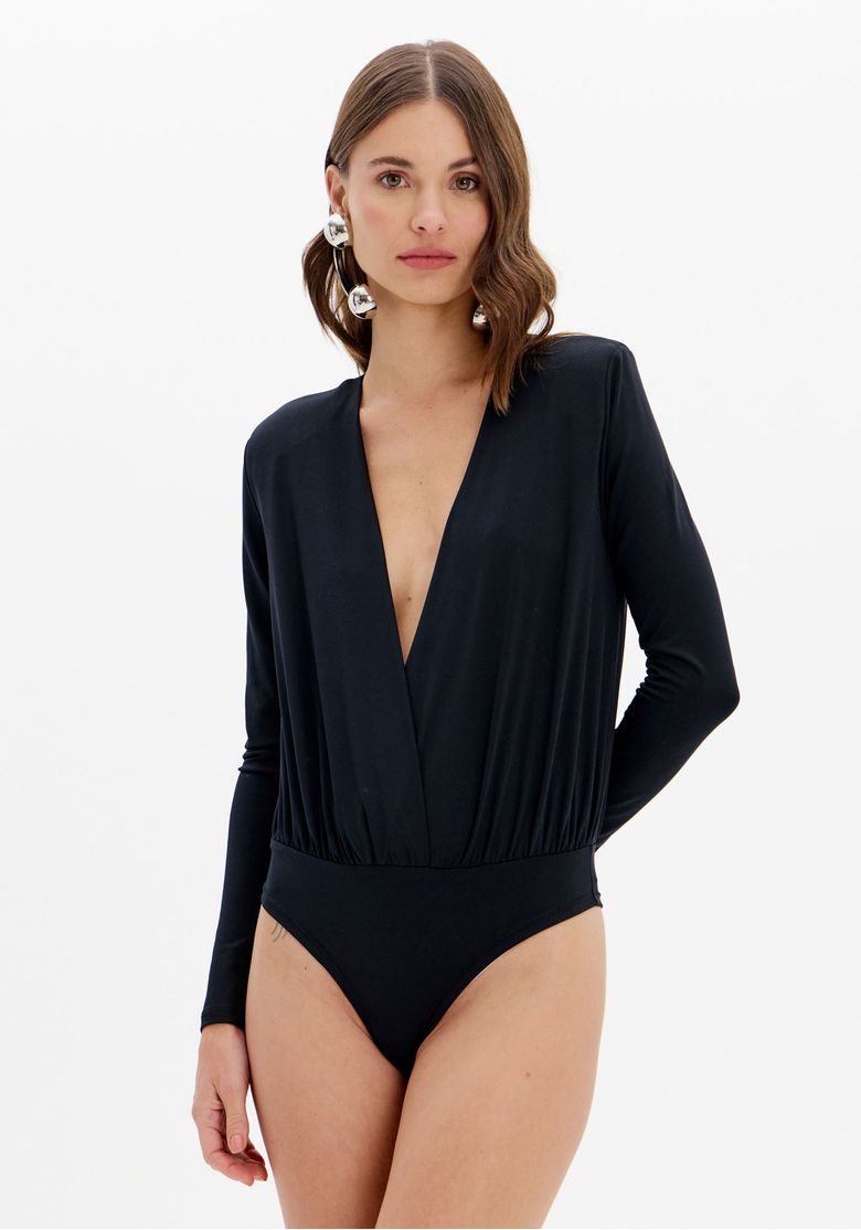 Modelo usando body preto manga longa transpassado com decote em V profundo e acabamento estilo calcinha, vista frontal completa em fundo neutro