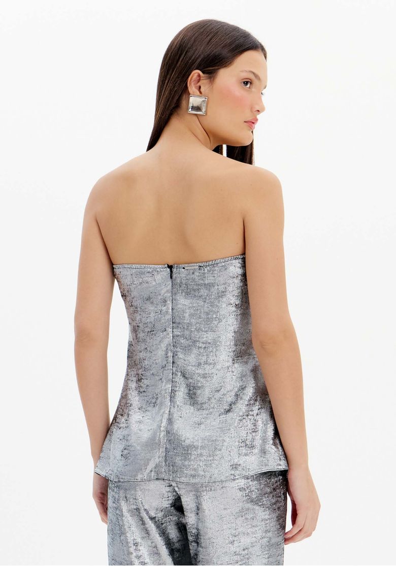 Vista traseira da blusa sem alças prateada mostrando o zíper nas costas e o comprimento alongado com caimento fluido