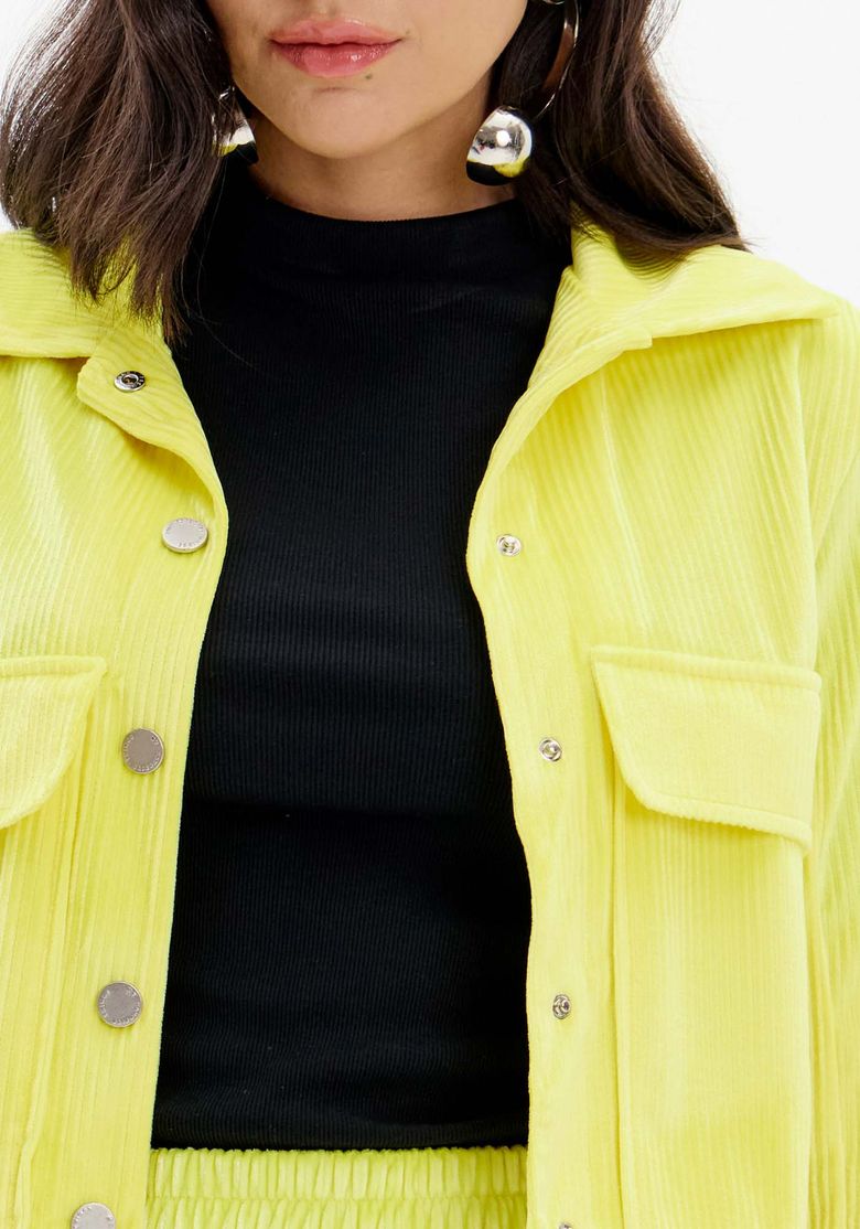 Look corpo inteiro com jaqueta cropped veludo amarelo e shorts combinando, modelo usando botas pretas cano médio