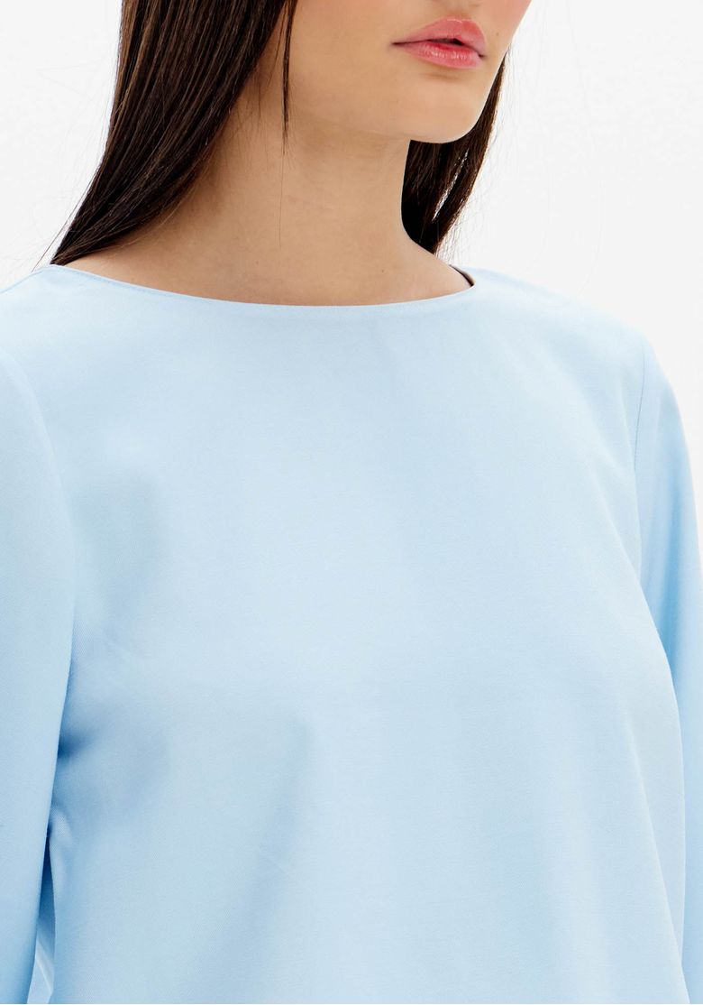 Detalhe da gola redonda e tecido leve da blusa azul.