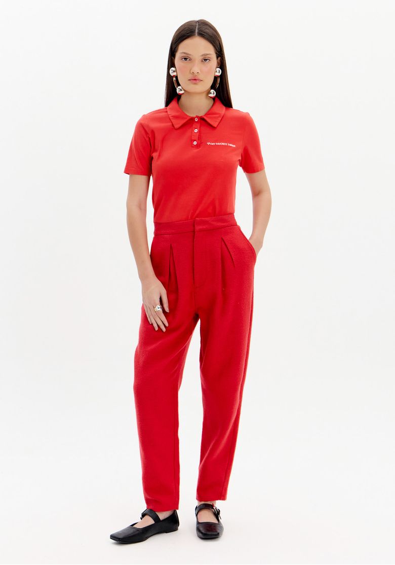 Modelo vestindo calça slouchy de alfaiataria vermelha com blusa polo combinando, vista frontal.