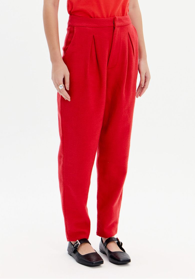 Detalhe da calça slouchy vermelha mostrando o cós com passantes e os bolsos embutidos.