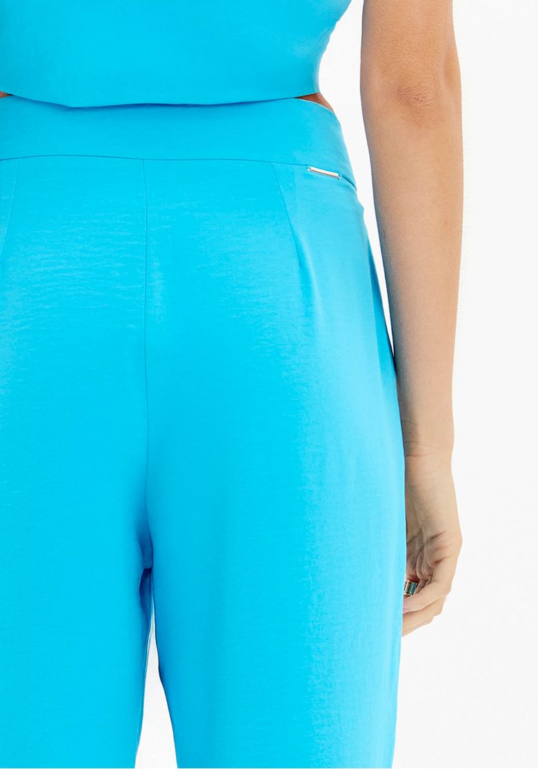 Detalhe do cós e parte traseira da calça azul, destacando o acabamento de alfaiataria e a textura do tecido plano leve.