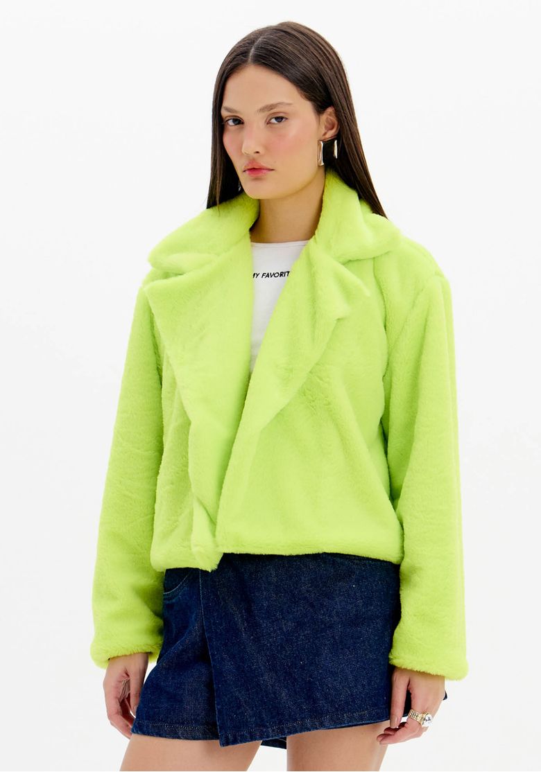 Mulher usando casaco teddy curto verde claro, vista frontal com saia jeans; casaco teddy curto feminino com gola de lapela e caimento solto.