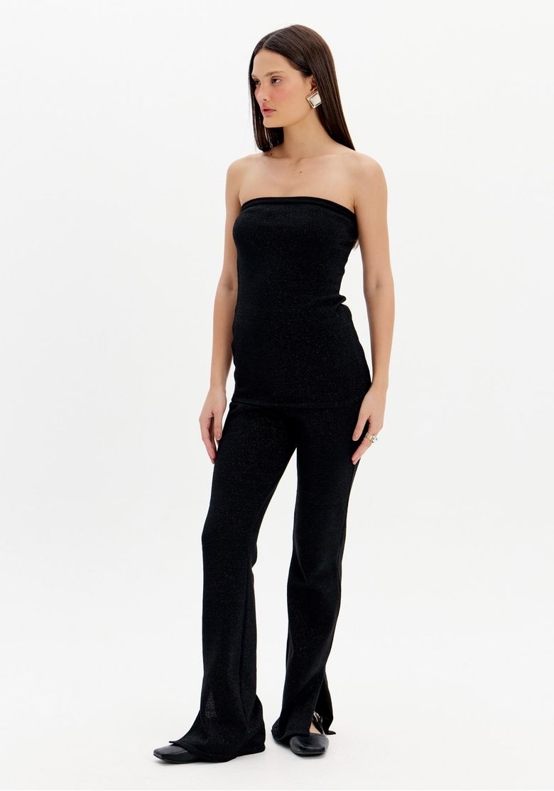 Modelo em estúdio usando calça tricô boot cut preta de cintura alta com top tomara que caia, vista 3/4