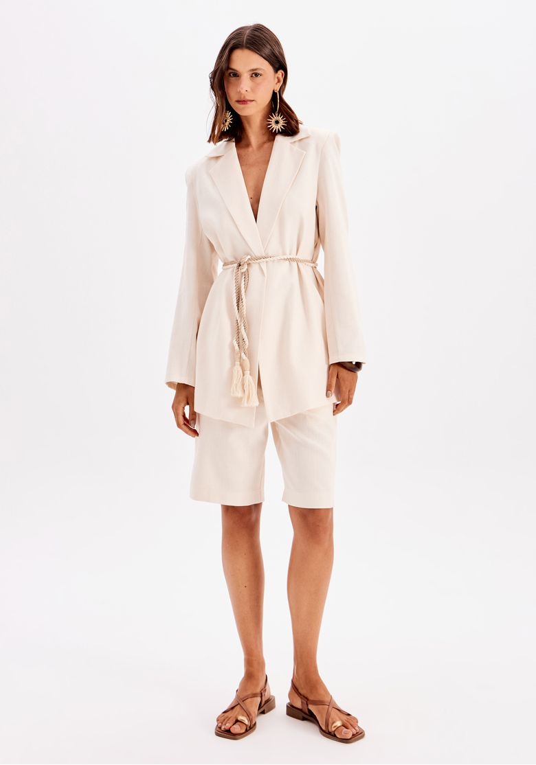 Modelo vestindo bermuda alongada branca com blazer combinando.