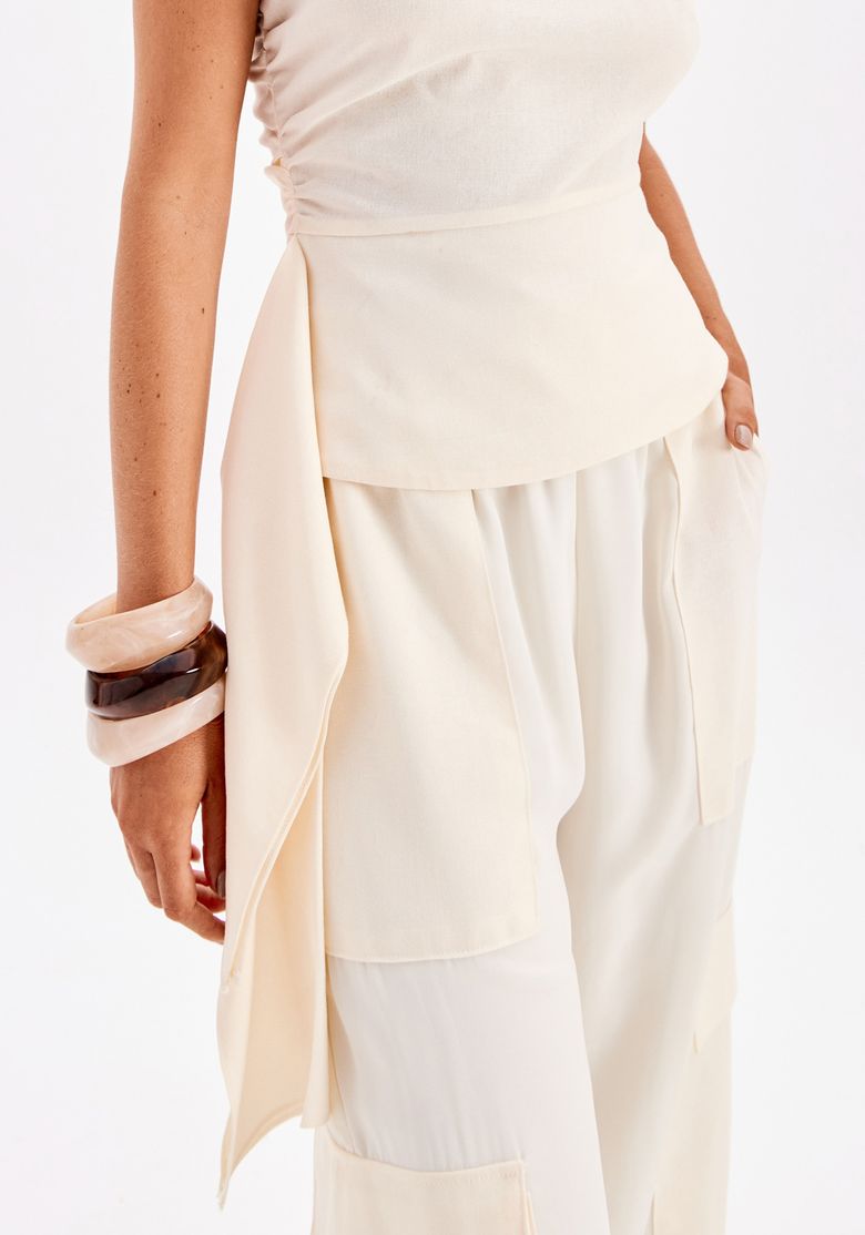 Detalhe da barra assimétrica da blusa branca feminina com recorte lateral fluido e acabamento elegante