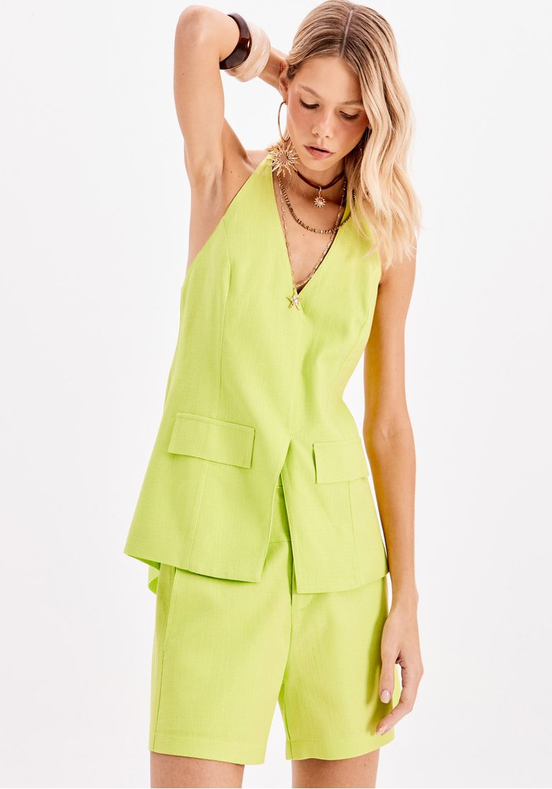 Close frontal da blusa frente única em verde mostrando recortes, sobreposição assimétrica e bolsos com lapela