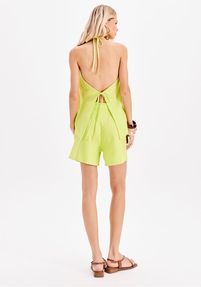 Vista traseira completa da modelo com blusa frente única verde e shorts, destacando a amarração e o caimento