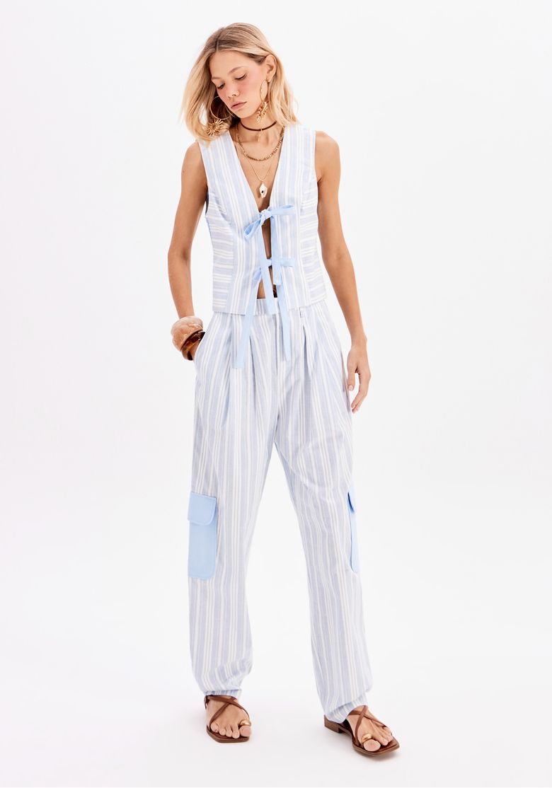 Modelo usando colete curto feminino listrado azul com amarração frontal e calça listrada de tecido leve em look casual urbano
