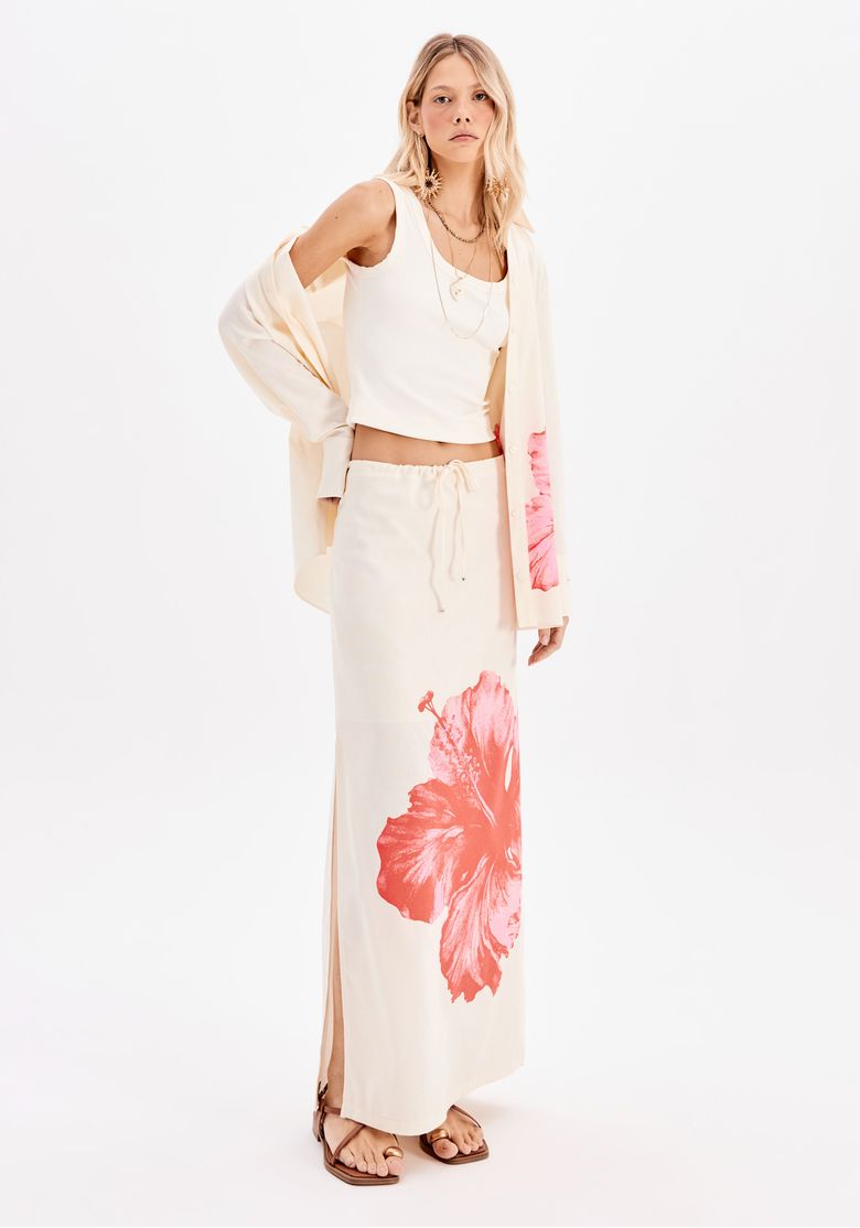 Modelo vestindo saia super midi com estampa floral maxi e top branco, em um ambiente interno.