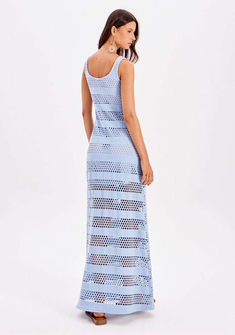 Perfil lateral da modelo com vestido super midi azul, evidenciando comprimento até o tornozelo e o caimento fluido