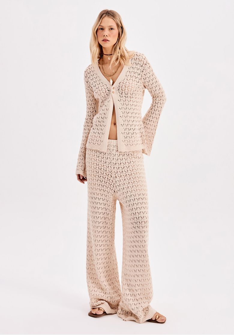 Modelo vestindo conjunto de tricô bege com calça reta e top de mangas longas.
