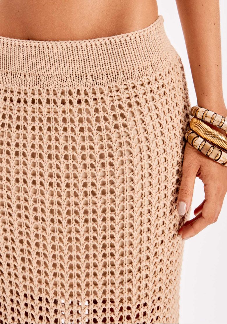 Detalhe posterior da saia tricot super midi bege com textura em ponto vazado e caimento reto até o tornozelo.