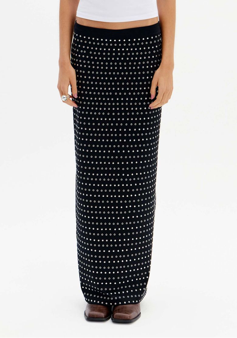 Modelo vestindo saia midi preta com brilhos e fenda lateral, combinada com camiseta branca.