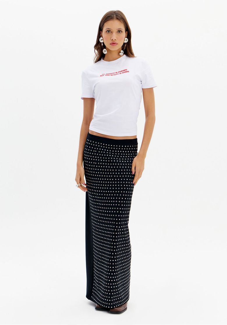 Modelo usando saia midi preta com brilhos, camiseta branca e blazer azul, criando um look sofisticado.
