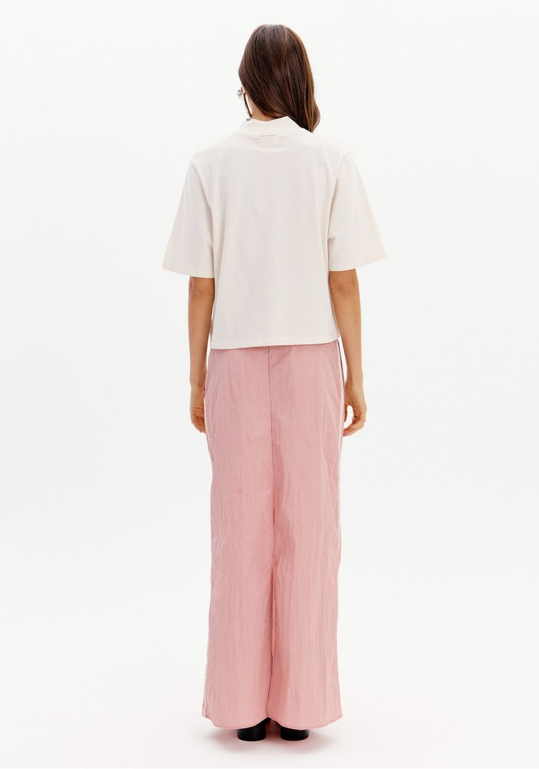 Modelo vestindo saia midi rosa com recortes e camisa branca vista de frente.