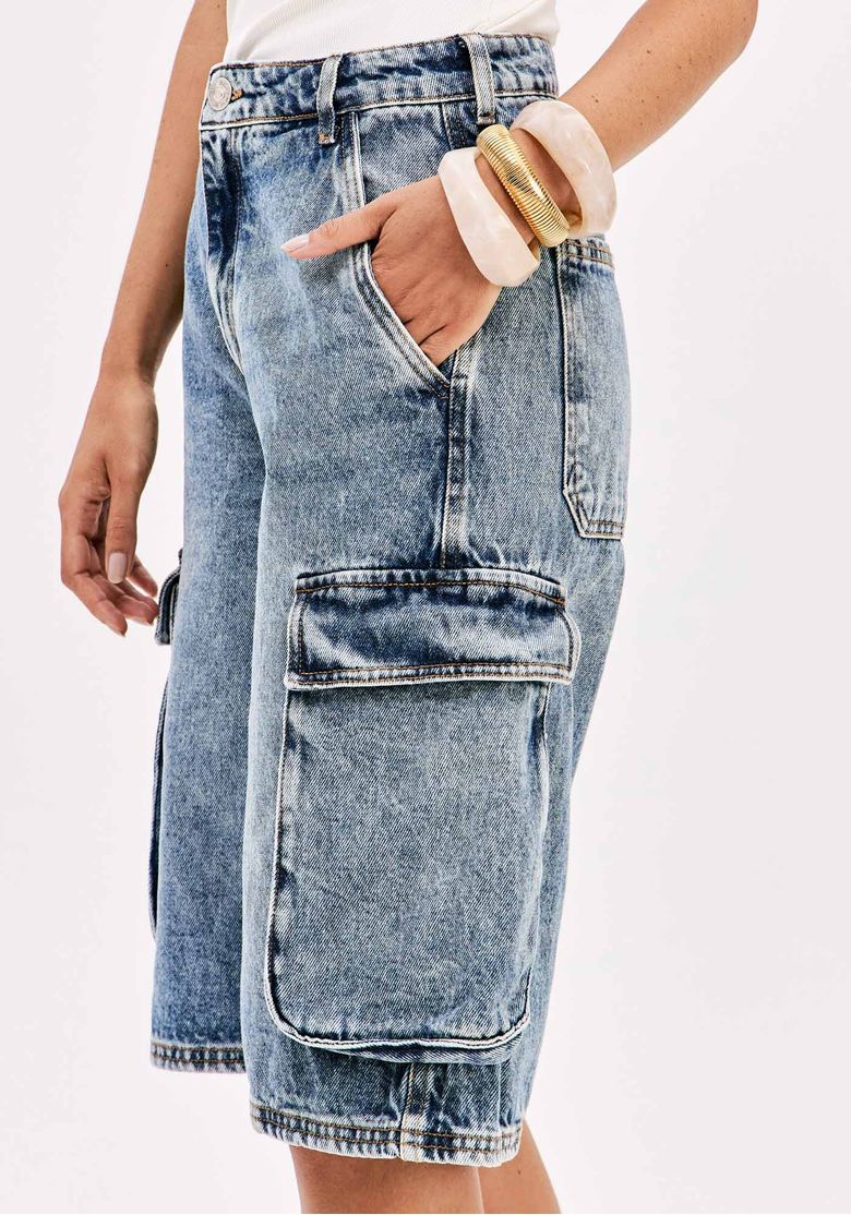 Detalhe lateral da bermuda jeans cargo mostrando os bolsos amplos.