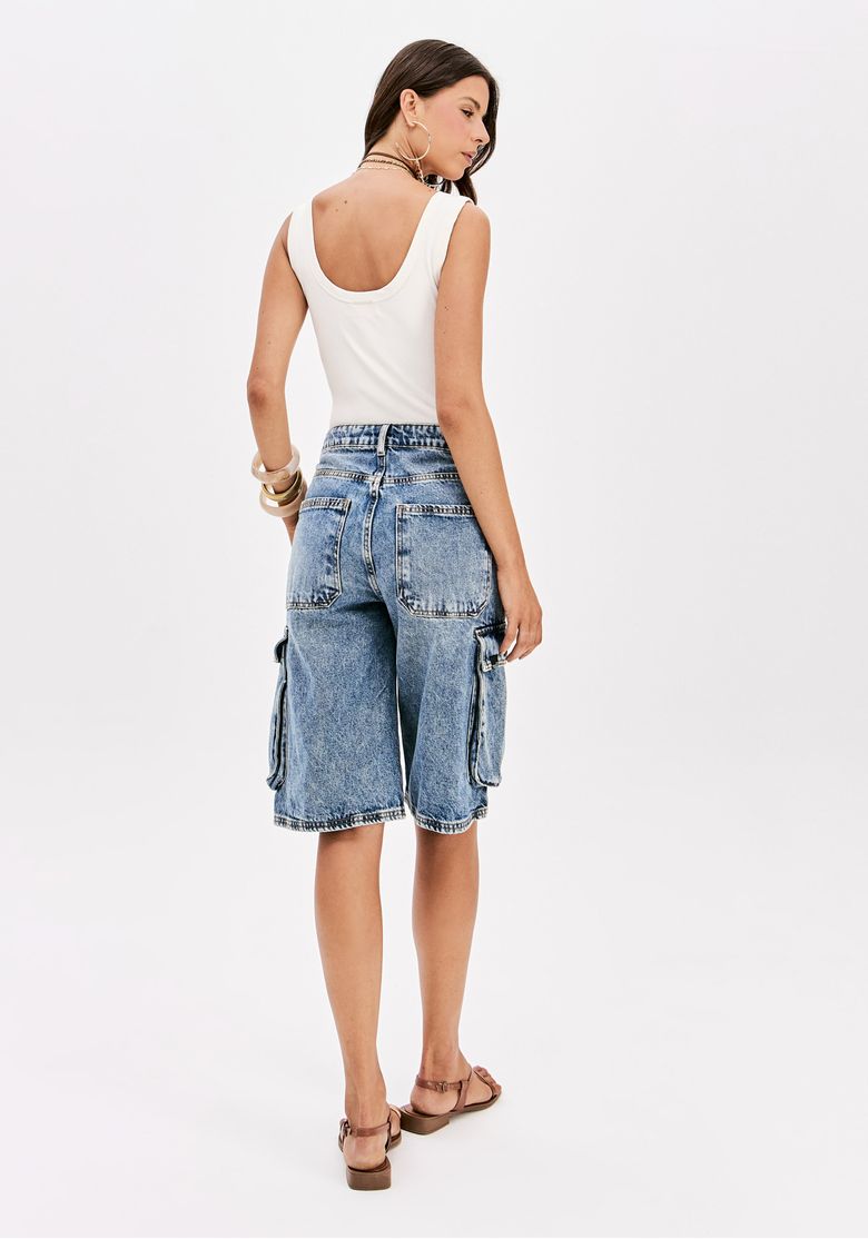 Modelo de costas vestindo bermuda jeans cargo e top branco.
