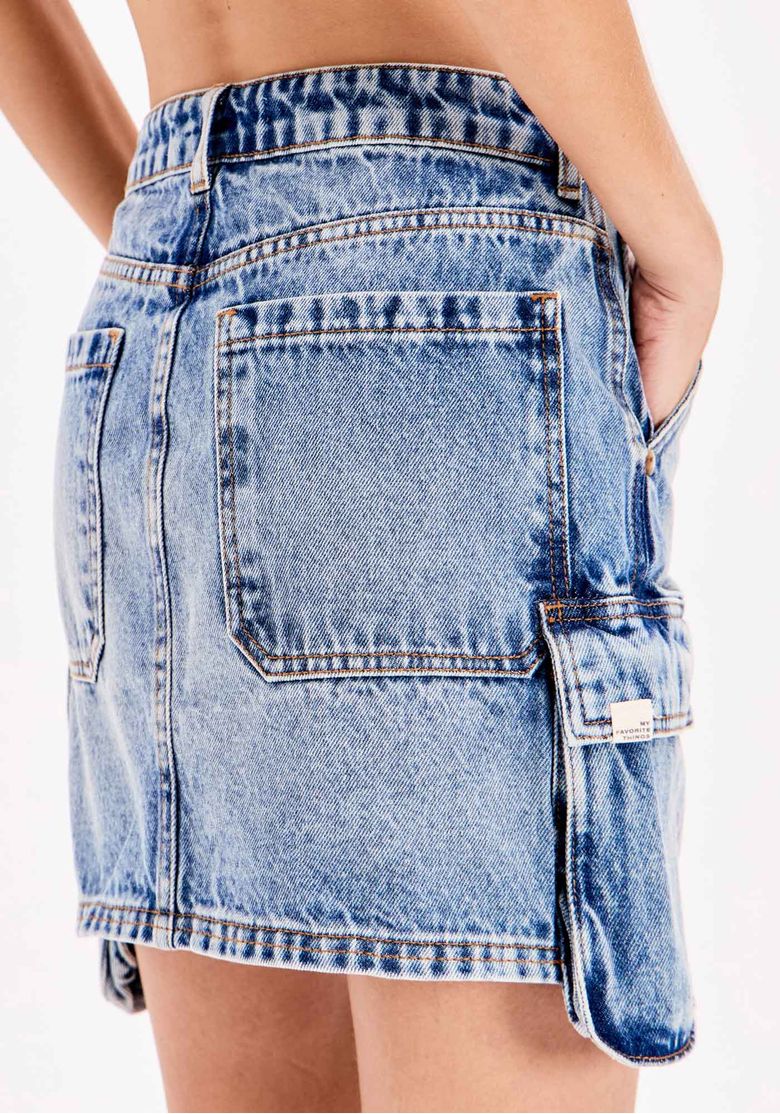 Vista frontal da saia jeans cargo curta, com bolsos funcionais na frente, cós com passantes e fechamento com botão e zíper.