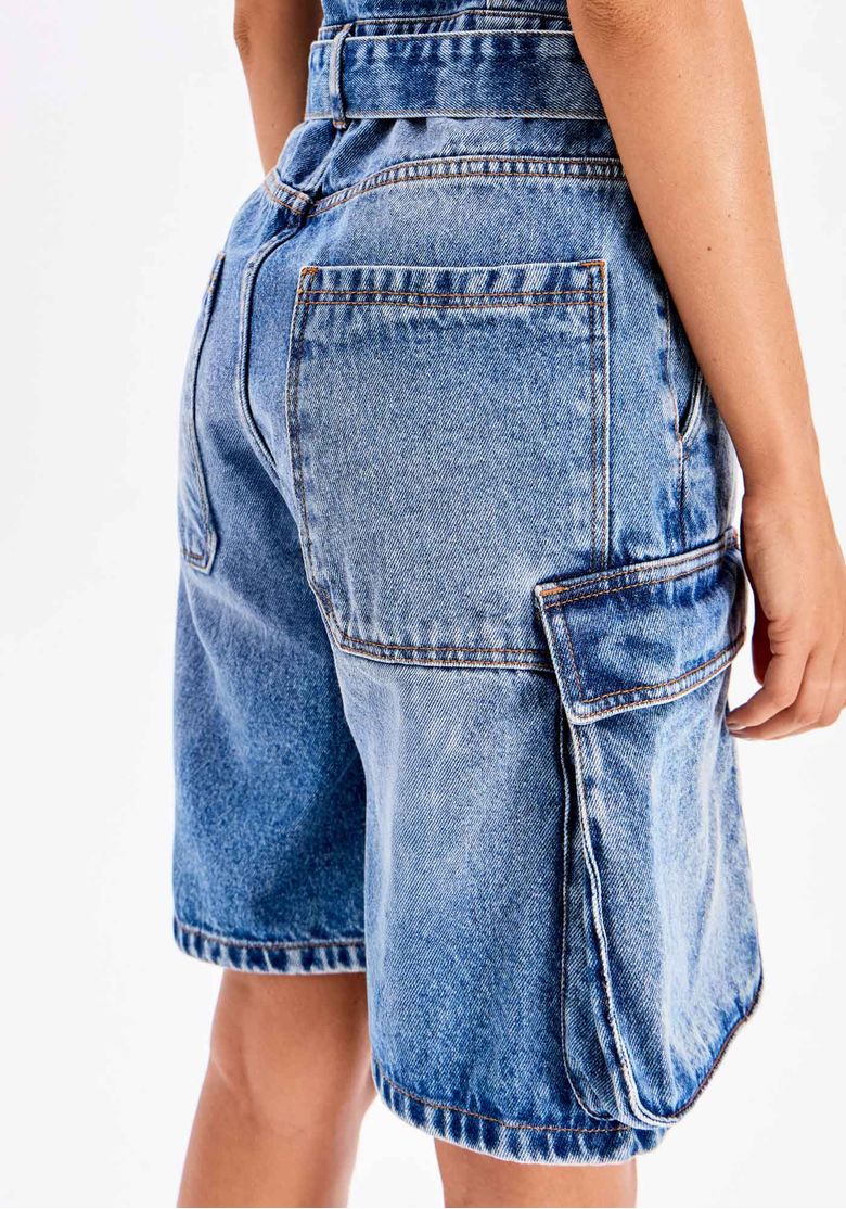 Close traseiro do macacão curto jeans azul com bolso posterior e bolso cargo lateral utilitário