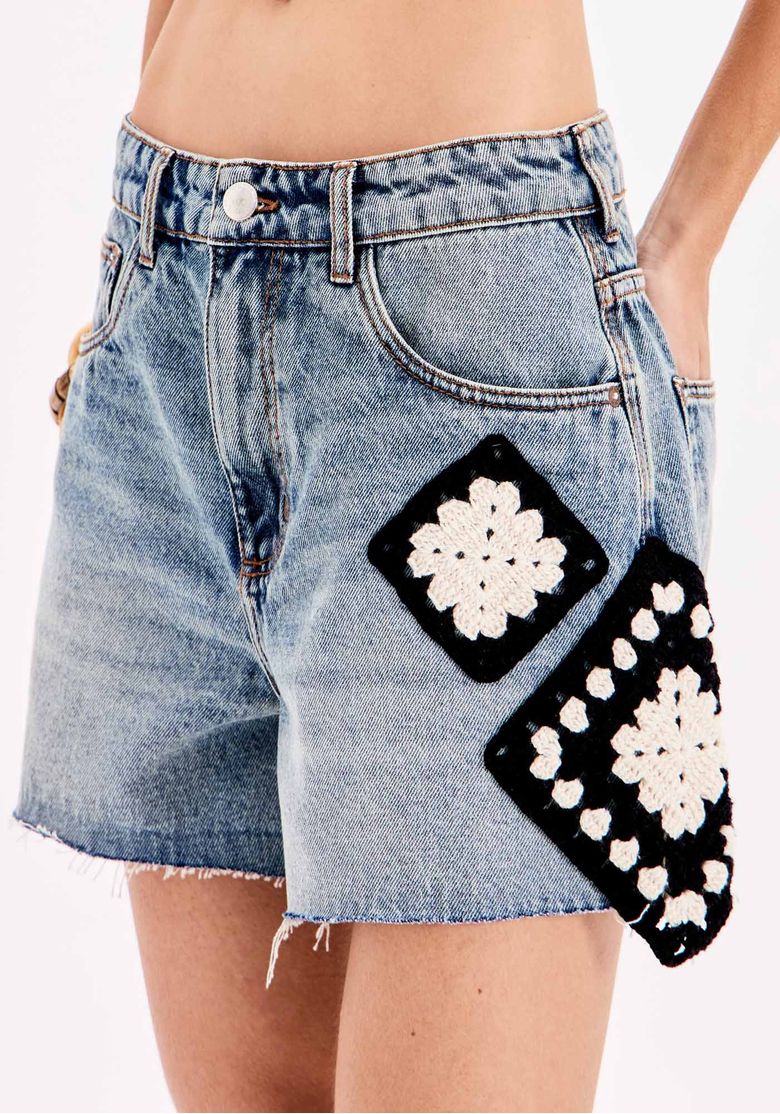 Detalhe da cintura alta e aplicações de crochê no short jeans.