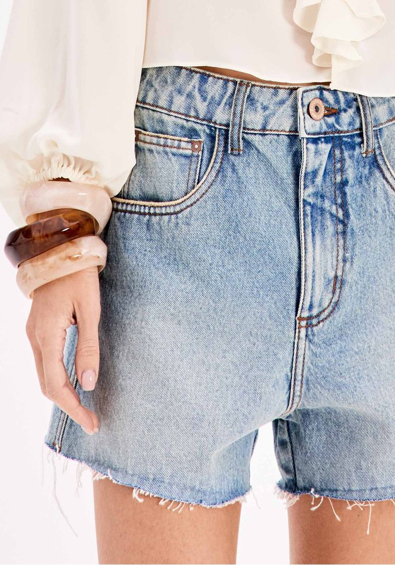 Visão traseira completa do short jeans azul com aplicação artesanal em crochê nos bolsos e acabamento desfiado na barra