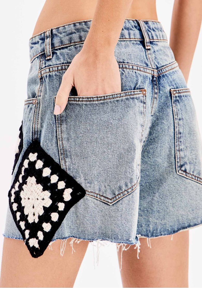 Modelo mostrando os bolsos funcionais do short jeans.