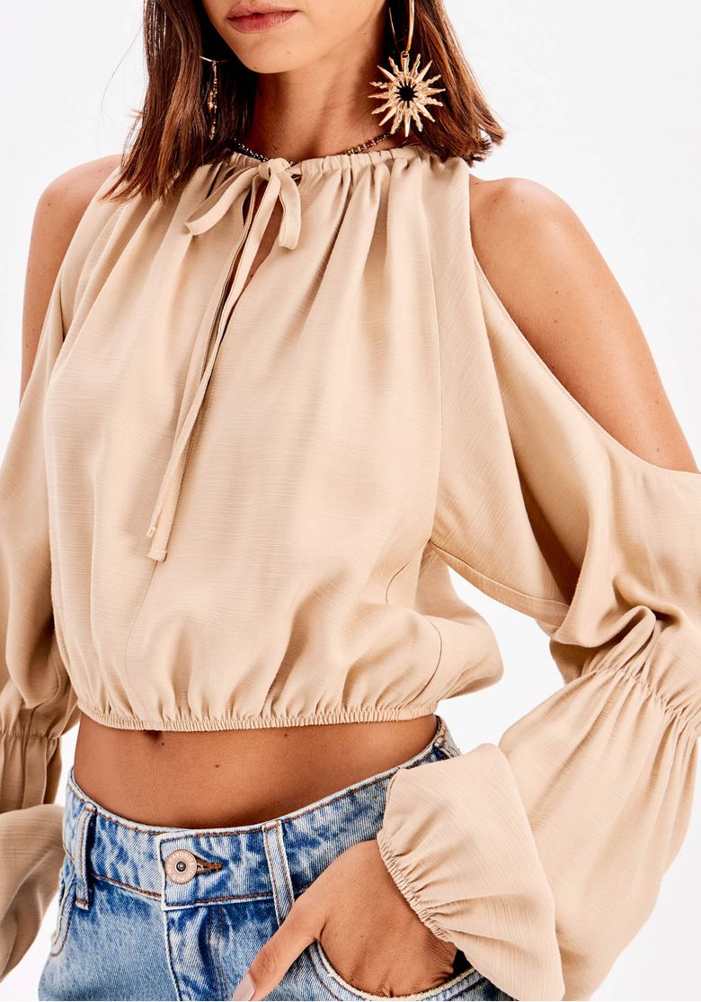 Detalhe traseiro da blusa cropped bege mostrando drapeado nas costas e abertura nos ombros (cold shoulder)