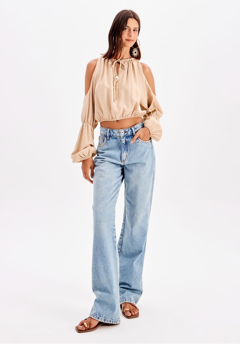 Vista posterior completa: blusa cropped bege com calça jeans lavagem clara e bolsos traseiros com aplicação em crochê