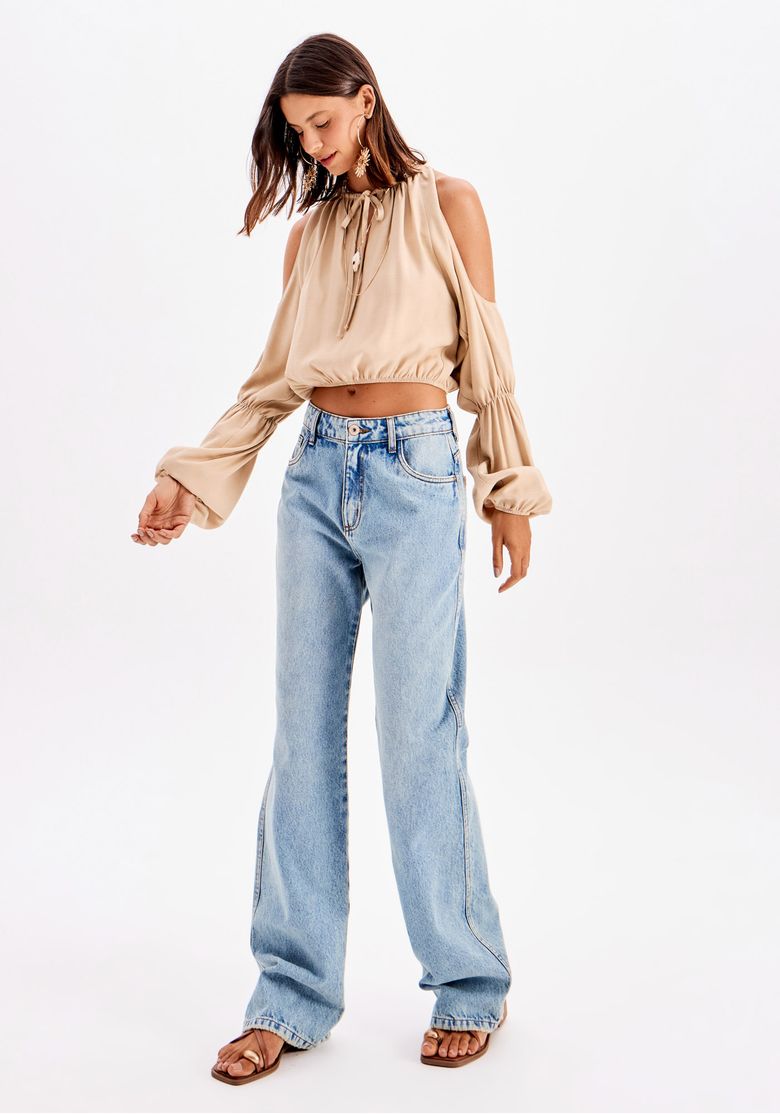 Modelo usando blusa cropped bege com manga longa ampla combinada com calça jeans cintura alta - look casual urbano full body