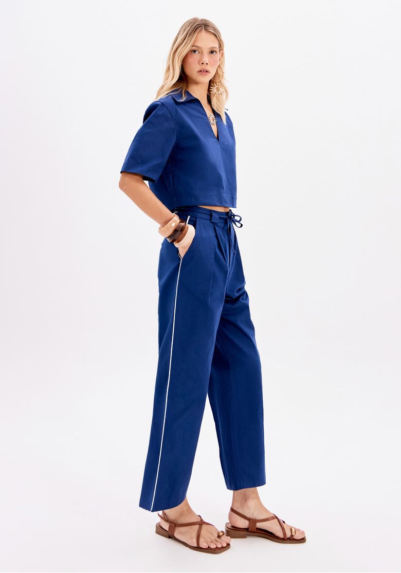 Blusa cropped azul feminina com gola polo e manga curta, vista lateral, em produção casual urbana