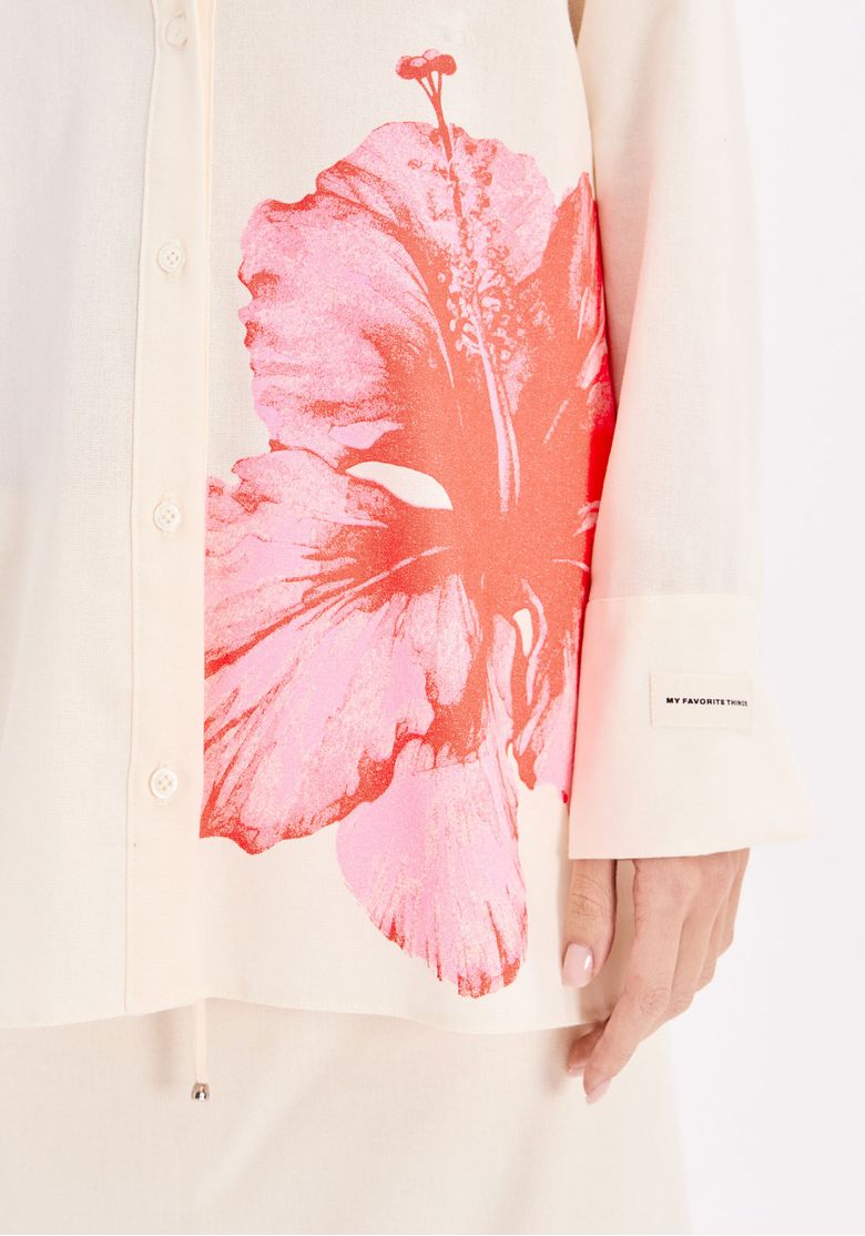 Close da camisa feminina estampada com flor tropical rosa, botões frontais e tecido claro com linho