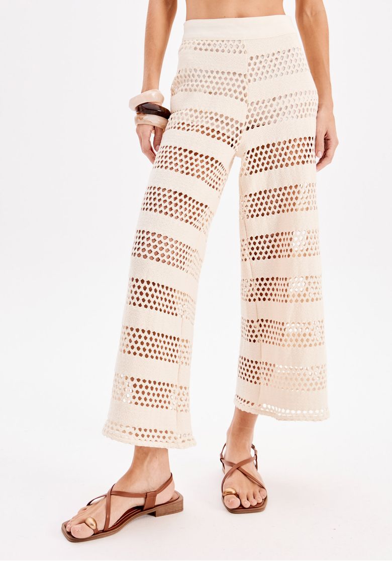 Vista traseira da calça reta vazada em off-white mostrando o cós largo e a textura em faixas geométricas, detalhe da barra