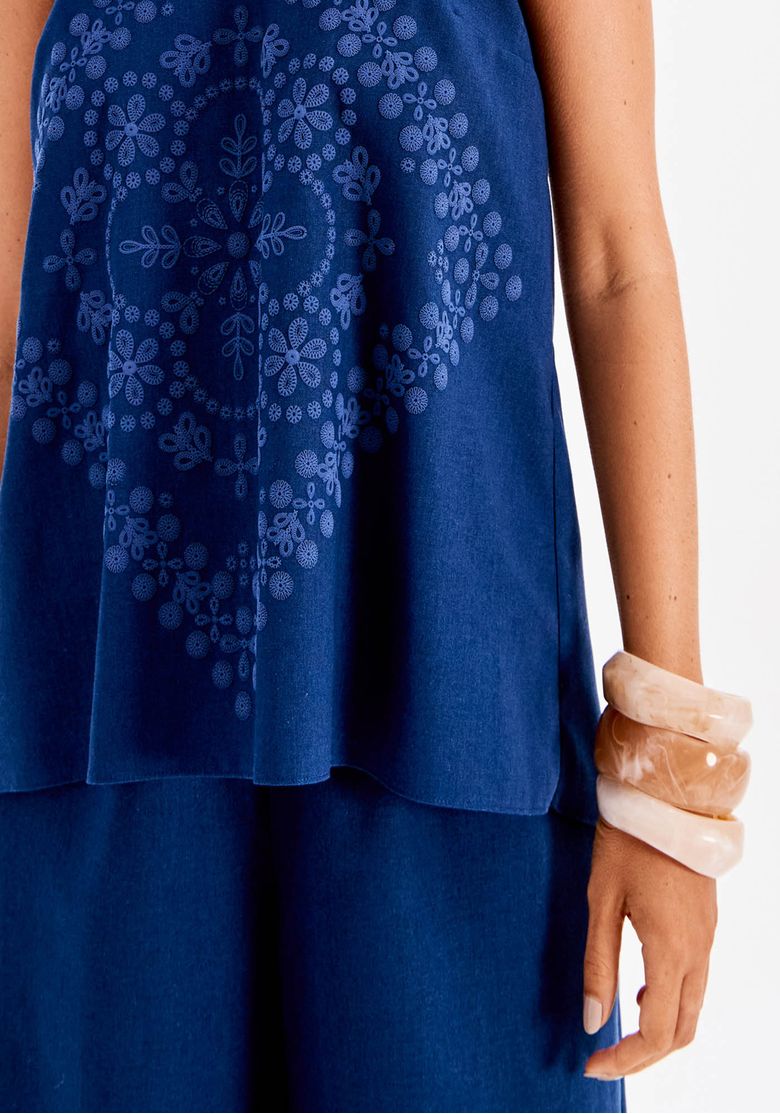 Close do comprimento e barra sobreposta da blusa frente única em azul, evidenciando o caimento fluido