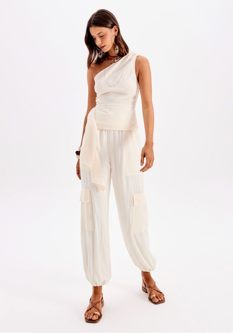 Modelo em pose frontal usando calça cargo branca em crepe com cós elástico e barra com elástico, look casual