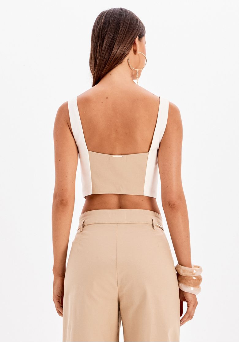 Modelo usando blusa corset bege com recortes contrastantes e calça pantalona bege em look casual urbano